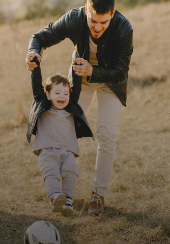 dad playing soccer with child