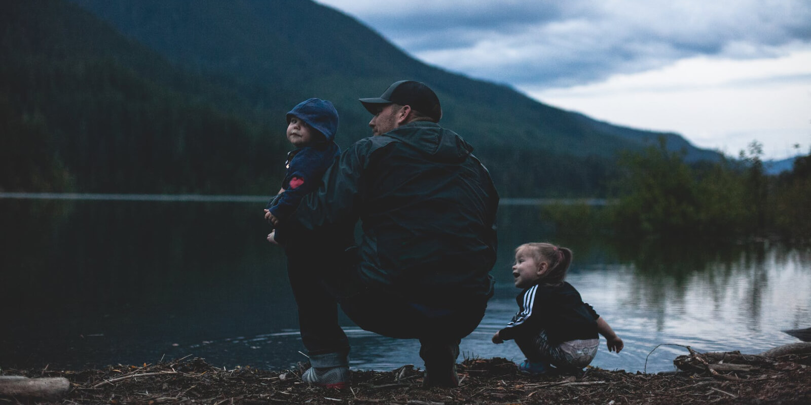 family crouched by mountain lake