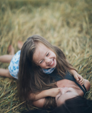 two young girls smiling laying in grass