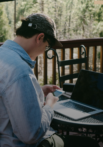 man using laptop and cellphone outside