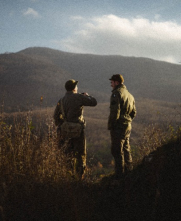 two people talking in front of big hill