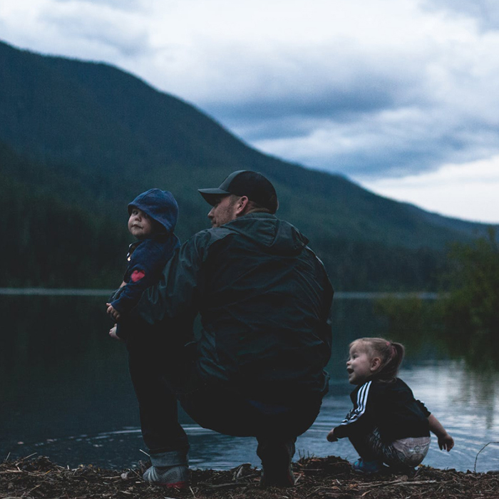 family sitting by mountain lake